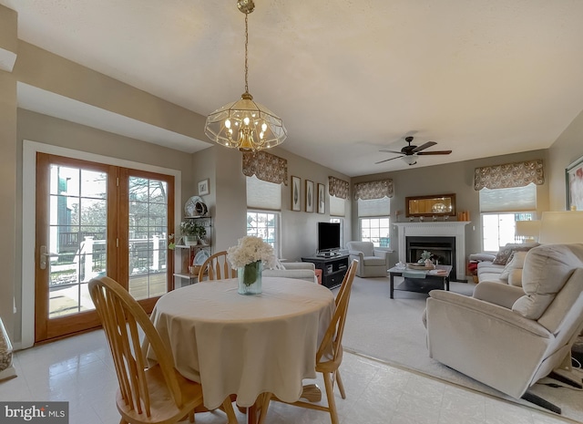 dining space with plenty of natural light, a fireplace, and ceiling fan with notable chandelier