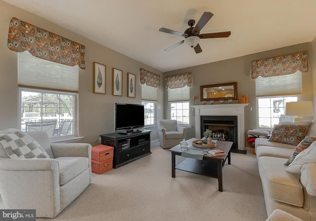 carpeted living room featuring a fireplace and ceiling fan