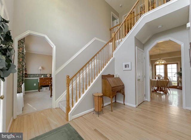 stairs featuring a chandelier, a high ceiling, and wood finished floors