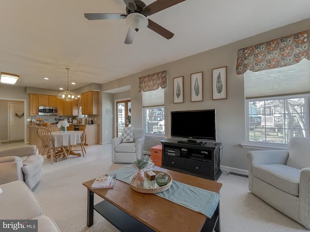 living area featuring light carpet, recessed lighting, ceiling fan with notable chandelier, and baseboards