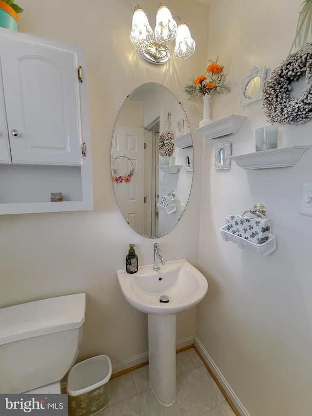 half bath with toilet, baseboards, and tile patterned floors