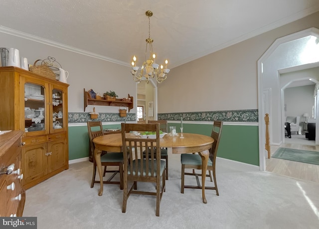 dining space featuring arched walkways, light carpet, a wainscoted wall, crown molding, and an inviting chandelier