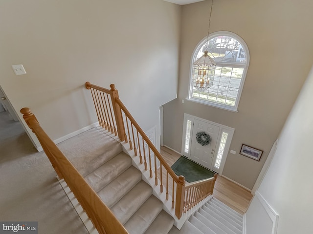 foyer entrance with wood finished floors, baseboards, a high ceiling, and an inviting chandelier