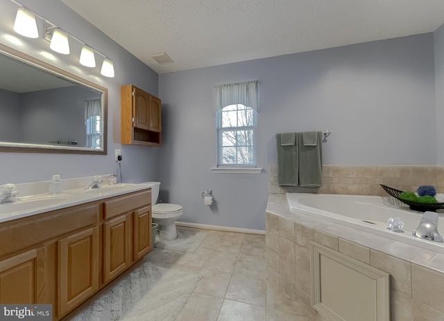 bathroom with a textured ceiling, tile patterned flooring, toilet, a garden tub, and a sink