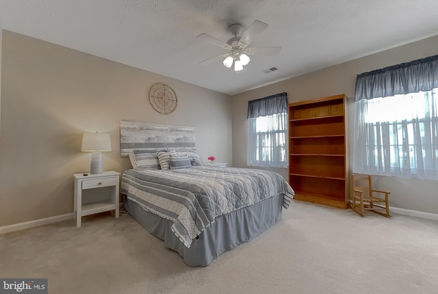 bedroom with visible vents, baseboards, ceiling fan, a textured ceiling, and carpet floors