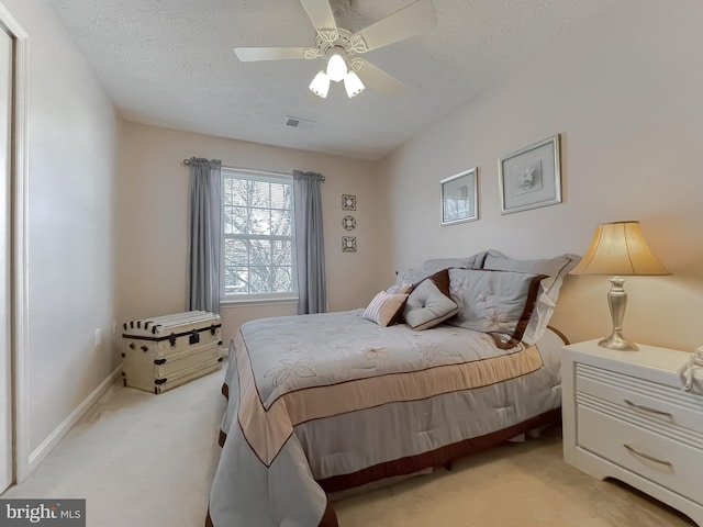 bedroom with light colored carpet, ceiling fan, visible vents, and a textured ceiling