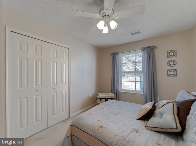 bedroom featuring a textured ceiling, visible vents, a closet, and light colored carpet