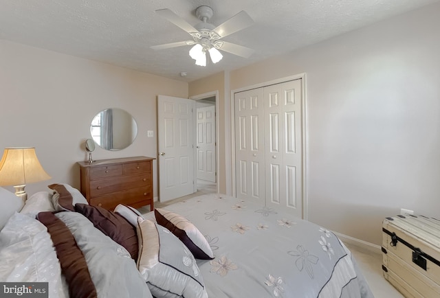 bedroom featuring a closet, a ceiling fan, light carpet, a textured ceiling, and baseboards