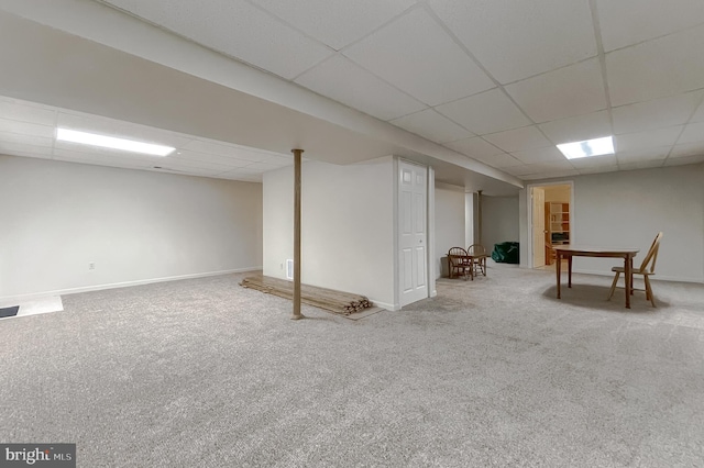 finished basement with carpet floors, a paneled ceiling, and baseboards