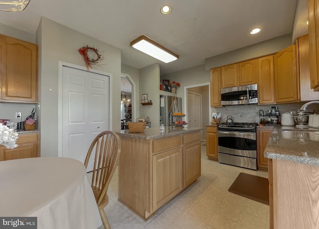 kitchen featuring arched walkways, stainless steel appliances, a sink, a center island, and light floors