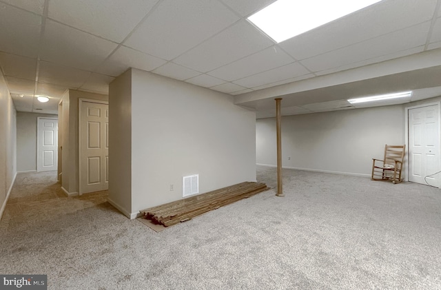 finished basement featuring carpet floors, baseboards, visible vents, and a drop ceiling