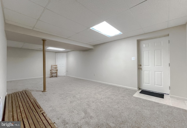 finished basement with carpet floors, a paneled ceiling, and baseboards