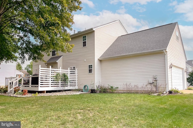 rear view of house featuring roof with shingles, a yard, a wooden deck, and an attached garage