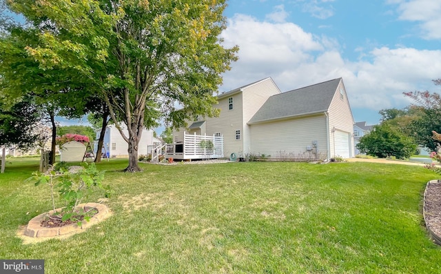 rear view of property with a deck, a yard, and an attached garage