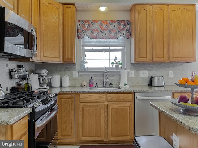 kitchen with appliances with stainless steel finishes, a sink, and tasteful backsplash