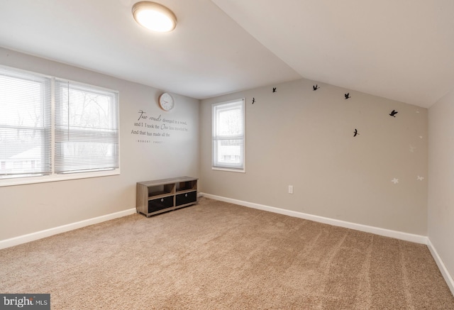 spare room featuring vaulted ceiling and light carpet