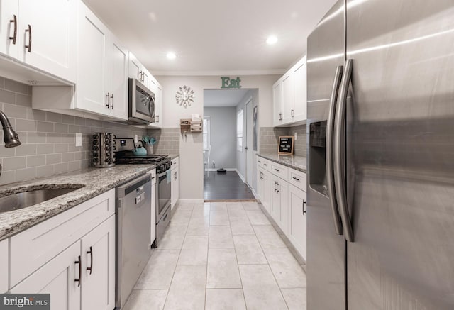 kitchen with light tile patterned flooring, sink, light stone counters, appliances with stainless steel finishes, and white cabinets