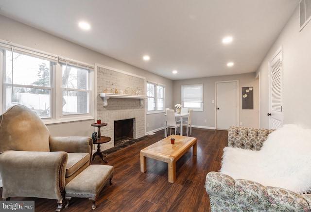 living room featuring dark hardwood / wood-style flooring and a brick fireplace