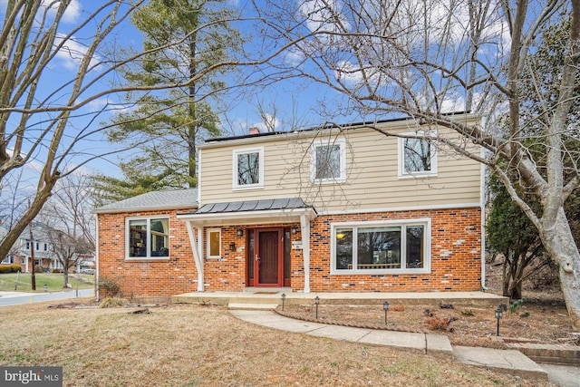 traditional home featuring a front yard and brick siding