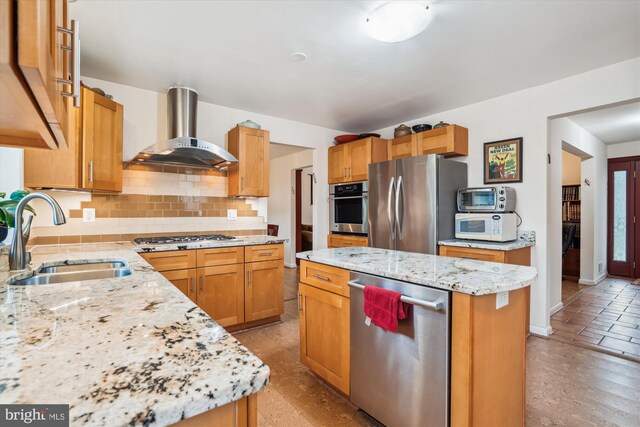 kitchen featuring stainless steel appliances, a kitchen island, a sink, wall chimney exhaust hood, and tasteful backsplash