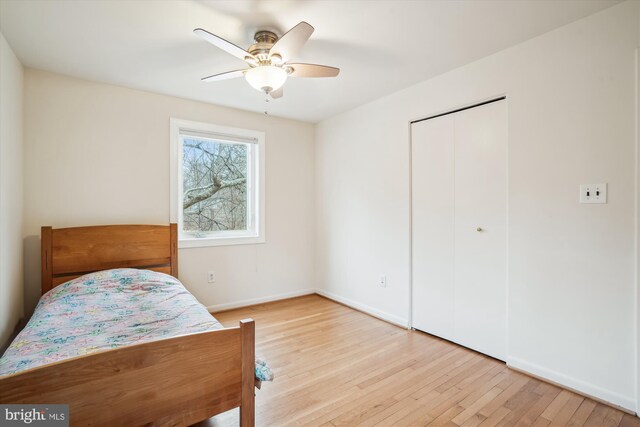 bedroom featuring light wood-type flooring, ceiling fan, baseboards, and a closet