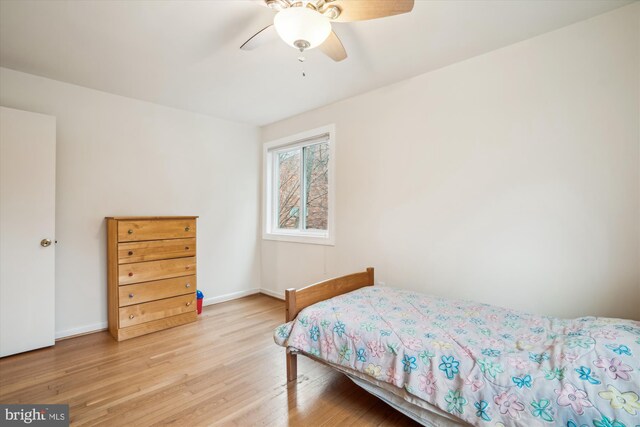 bedroom with ceiling fan, light wood-style flooring, and baseboards