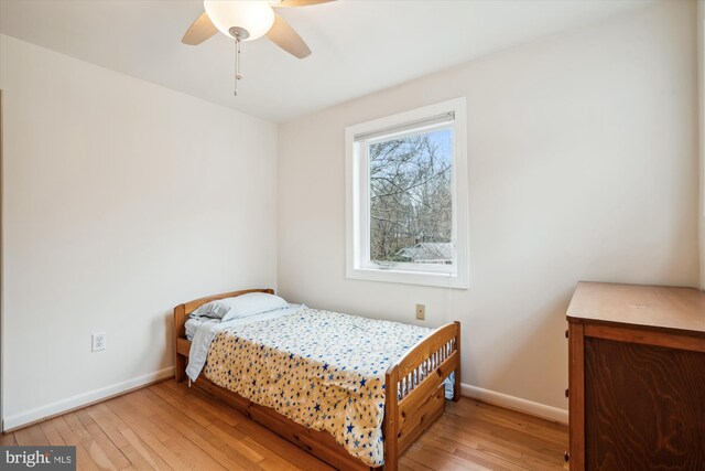 bedroom featuring light wood-type flooring, baseboards, and a ceiling fan