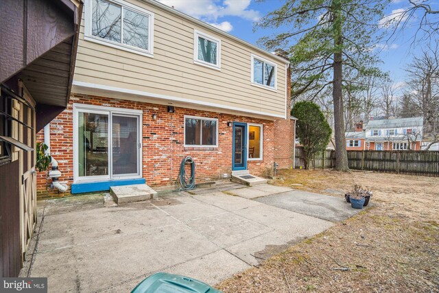 back of property featuring entry steps, brick siding, a patio, and a fenced backyard