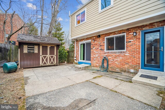 view of patio featuring fence, a storage unit, and an outdoor structure