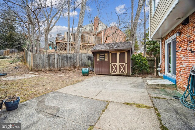 view of patio / terrace with an outbuilding, a storage unit, and a fenced backyard