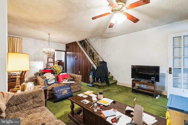 carpeted living room with ceiling fan with notable chandelier and a textured ceiling