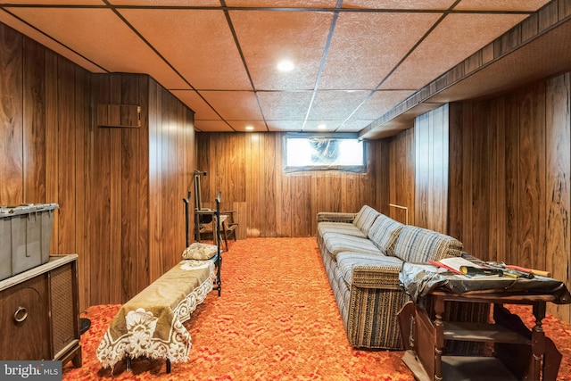 sitting room featuring a drop ceiling and wooden walls