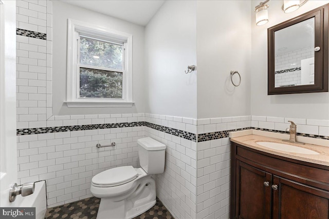 bathroom with vanity, toilet, and tile walls