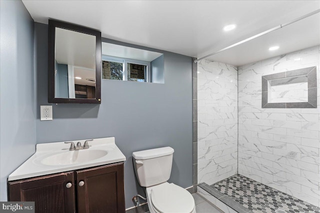 bathroom with vanity, tiled shower, and toilet