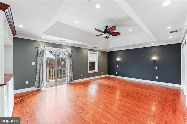 unfurnished living room with ornamental molding, a tray ceiling, and light hardwood / wood-style flooring