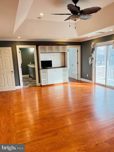 unfurnished living room featuring a tray ceiling, wood-type flooring, and ceiling fan