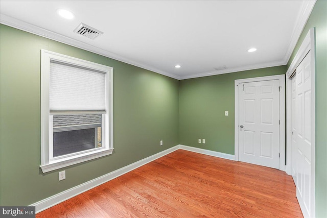 spare room featuring crown molding and light hardwood / wood-style floors