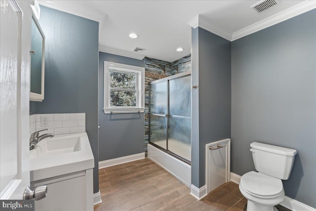 full bathroom featuring toilet, ornamental molding, vanity, enclosed tub / shower combo, and hardwood / wood-style floors