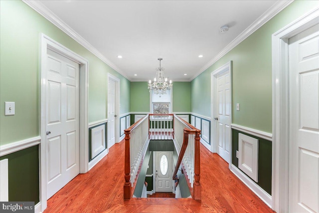 hall featuring crown molding, light hardwood / wood-style floors, and a chandelier