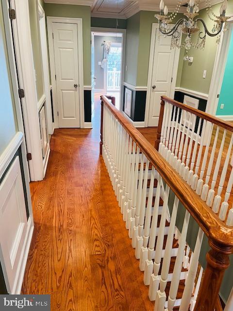 corridor featuring crown molding, hardwood / wood-style floors, and a chandelier