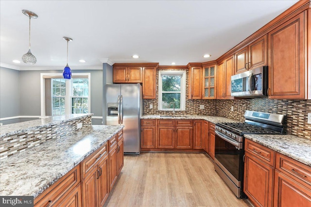 kitchen featuring pendant lighting, sink, light hardwood / wood-style flooring, appliances with stainless steel finishes, and ornamental molding