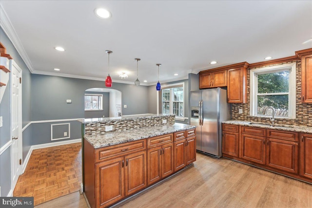 kitchen featuring decorative light fixtures, sink, stainless steel fridge, backsplash, and a center island