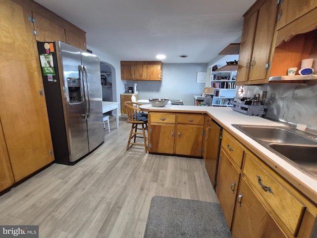 kitchen featuring sink, a breakfast bar area, stainless steel fridge with ice dispenser, light wood-type flooring, and kitchen peninsula