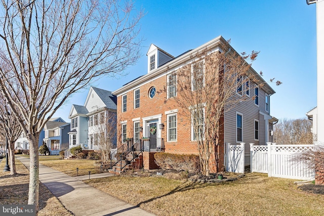 exterior space with brick siding, a front yard, fence, and a residential view