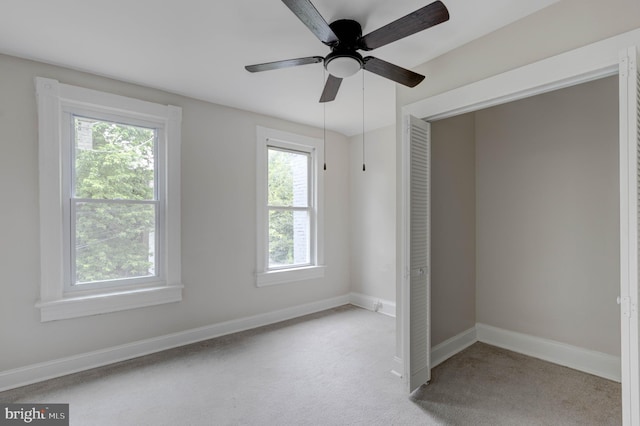 unfurnished bedroom with ceiling fan, light colored carpet, and a closet