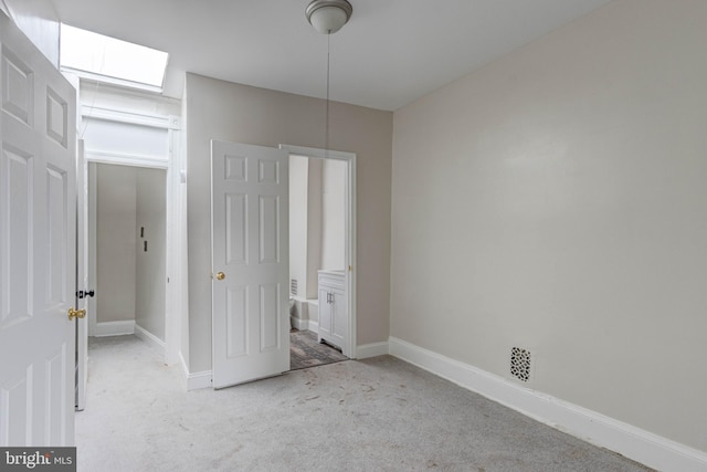 unfurnished bedroom with light colored carpet and a skylight