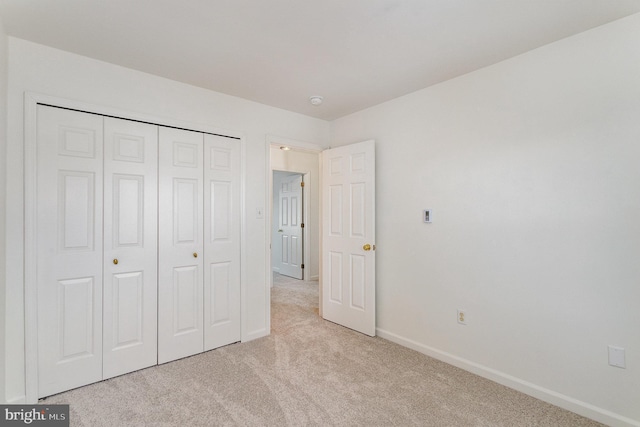 unfurnished bedroom with a closet and light carpet