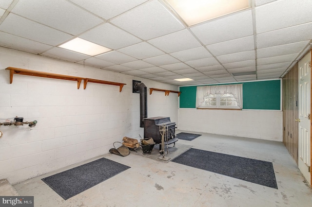 basement with a wood stove and a drop ceiling