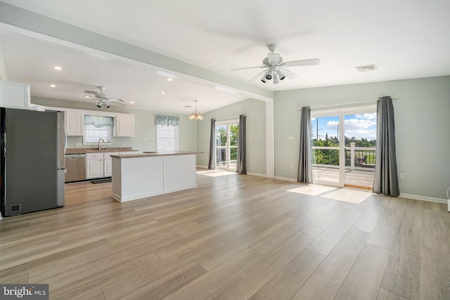 interior space featuring sink, appliances with stainless steel finishes, white cabinetry, light hardwood / wood-style floors, and a kitchen island