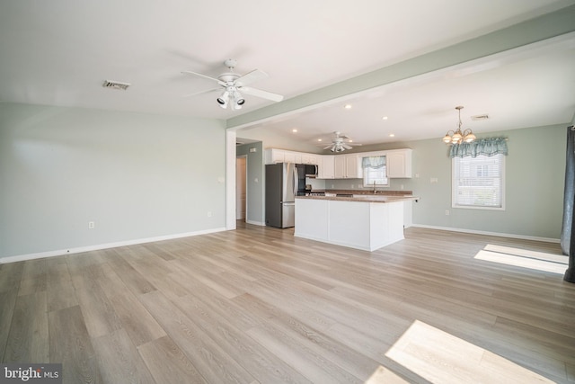 unfurnished living room featuring beamed ceiling, sink, ceiling fan with notable chandelier, and light wood-type flooring